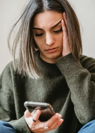 A stock image of a woman using a phone, looking disappointed.
